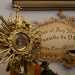 Una consolle ospita vari oggetti votivi o religiosi: un libro di preghiere, un ostensorio al cui interno si intravede una reliquia...